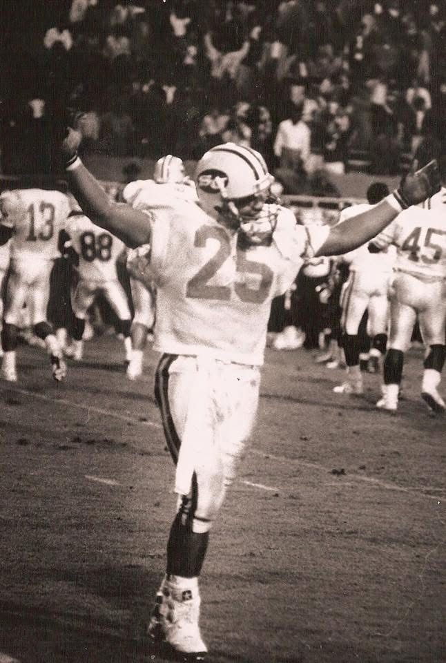 Coach Sean Wallace in his Southern University number 25 jersey, arms raised on the field